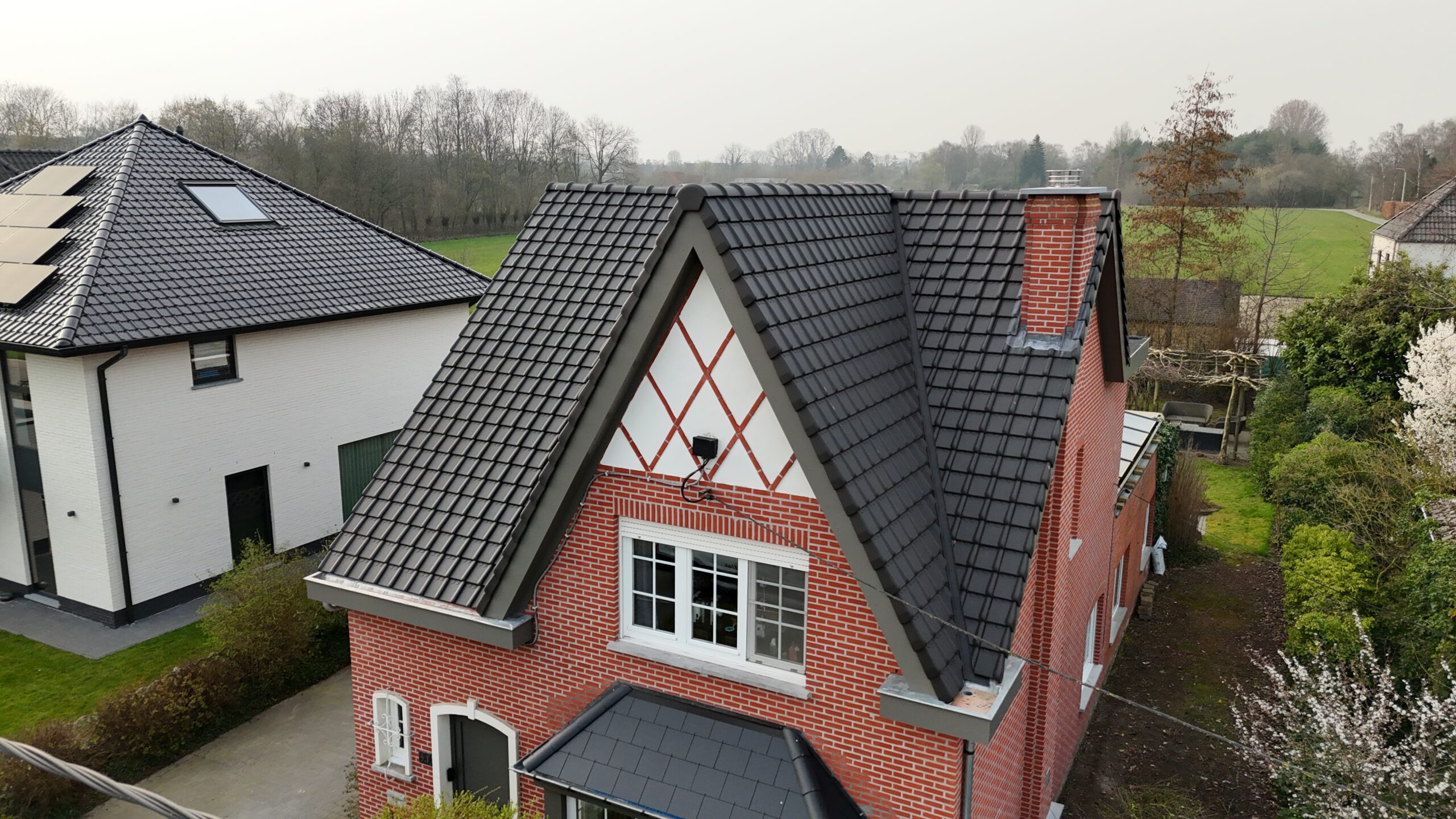Luchtfoto van een woning in rode baksteen met vernieuwd antracietgrijs pannendak
